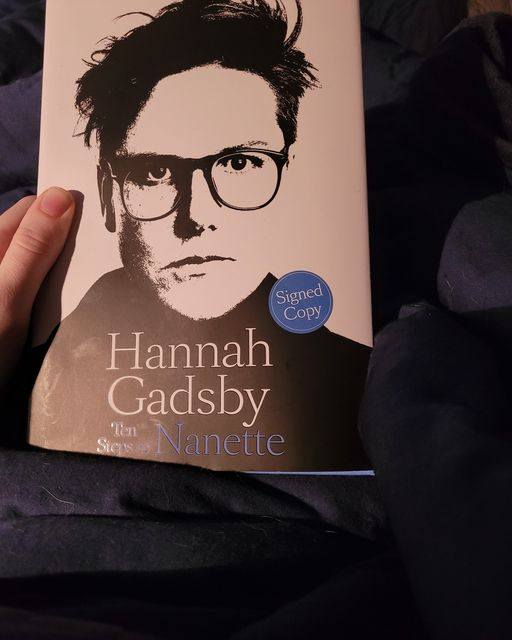A photo of a hardcover copy of Hannah Gadsby's 2022 book, Ten Steps to Nanette. The cover shows a black and white photo of the author and says it is a signed copy.